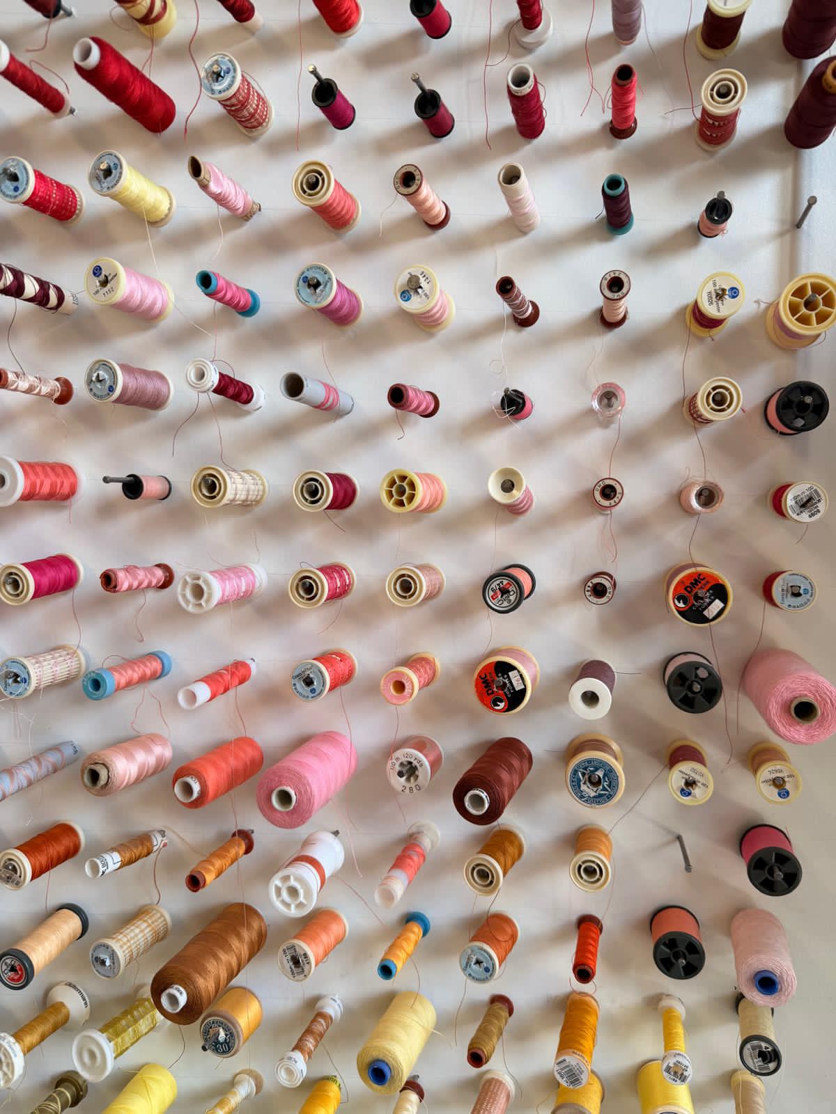 Mur de bobines de fil de couleurs variées dans l'atelier